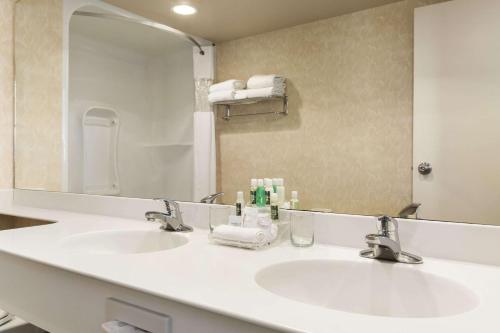 La salle de bains est pourvue de 2 lavabos et d'un grand miroir. dans l'établissement Travelodge by Wyndham Spruce Grove, à Spruce Grove