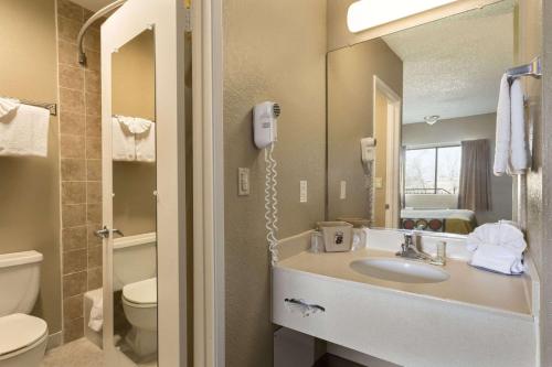 a bathroom with a sink and a toilet and a mirror at Super 8 by Wyndham Ridgecrest in Ridgecrest