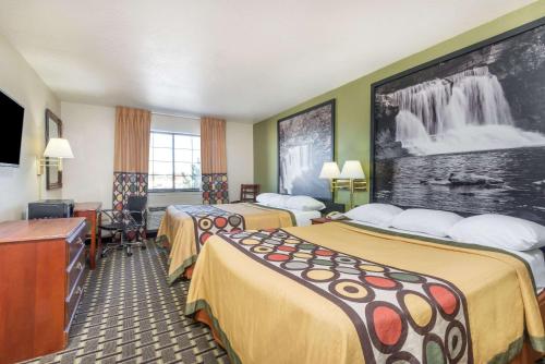 a hotel room with two beds and a flat screen tv at Super 8 by Wyndham Madison IN in Madison