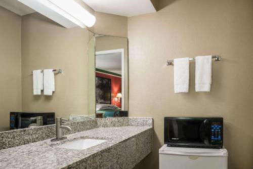 a bathroom with a sink and a television on a counter at Super 8 by Wyndham Little Rock/Otter Creek in Little Rock