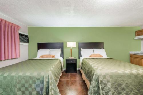 2 camas en una habitación con paredes verdes en Executive Inn & Kitchenette Suites-Eagle Pass, en Eagle Pass