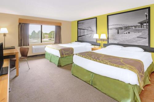 a hotel room with two beds and a desk at Super 8 by Wyndham Davenport in Davenport