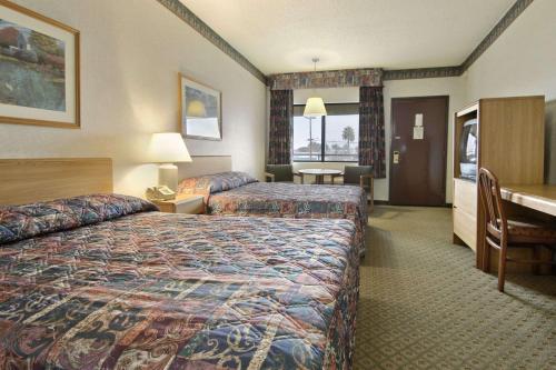 a hotel room with two beds and a desk at Travelodge by Wyndham Commerce Los Angeles Area in Commerce