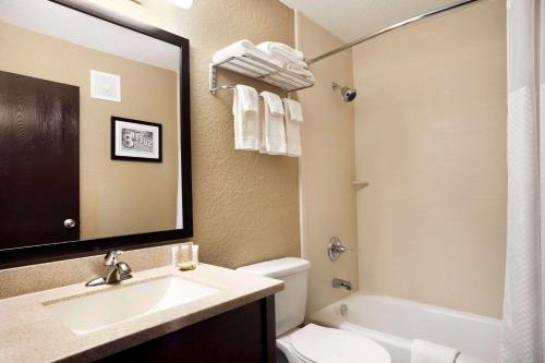 a bathroom with a sink and a toilet and a mirror at Super 8 by Wyndham Joplin in Joplin
