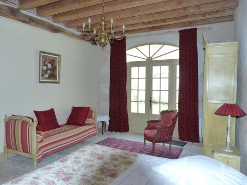 ein Schlafzimmer mit einem Bett, einem Sofa und einem Stuhl in der Unterkunft Le Clos de la Chesneraie in Saint-Georges-sur-Cher