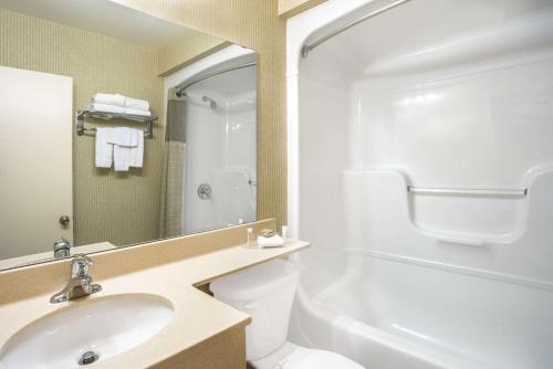 a bathroom with a sink and a toilet and a mirror at Super 8 by Wyndham Kingston in Kingston