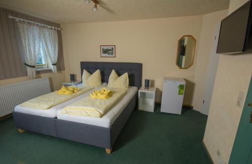 a bedroom with a large bed with yellow pillows at Pension Immergrün in Kurort Jonsdorf