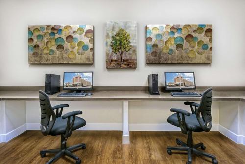 an office with two computers on a desk with four paintings at Hawthorn Extended Stay by Wyndham McAllen in McAllen