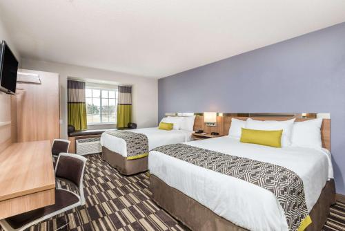 a hotel room with two beds and a television at Microtel Inn & Suites by Wyndham Beaver Falls in Beaver Falls
