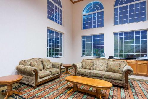 a living room with two couches and tables and windows at Super 8 by Wyndham Harrisburg Hershey North in Harrisburg
