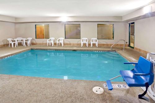a swimming pool with a blue chair and chairs at Super 8 by Wyndham South Bend in South Bend