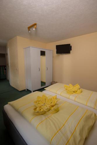 two beds in a room with yellow towels on them at Pension Immergrün in Kurort Jonsdorf