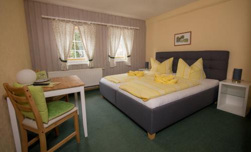 a bedroom with a bed and a table and a chair at Pension Immergrün in Kurort Jonsdorf