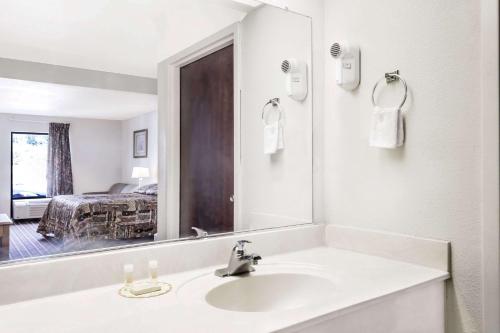 Baño blanco con lavabo y espejo en Brentwood Inn & Suites, en Suffolk