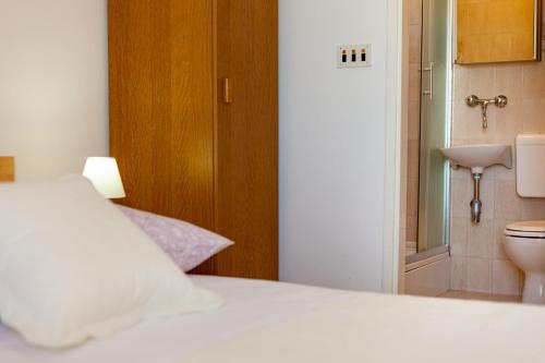 a bedroom with a white bed and a toilet at Rooms Marinac in Podstrana