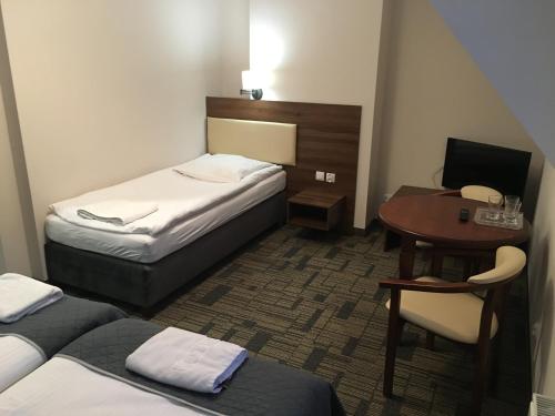 a hotel room with two beds and a desk and a table at Centrum Promocji Leśnictwa w Mucznem in Lutowiska