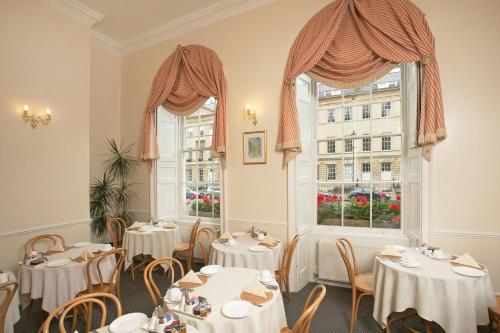 a restaurant with tables and chairs and two windows at Edgar Townhouse in Bath