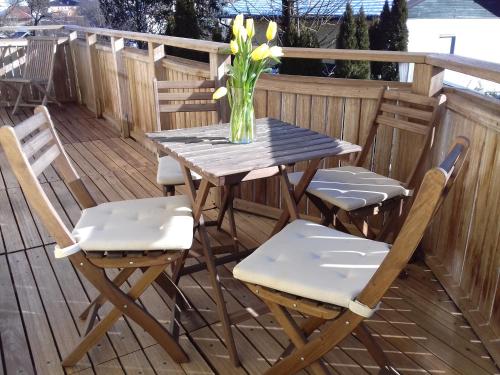 a table and chairs on a deck with a vase of flowers at Ferienwohnung Wiesmühlstrasse in Henndorf am Wallersee