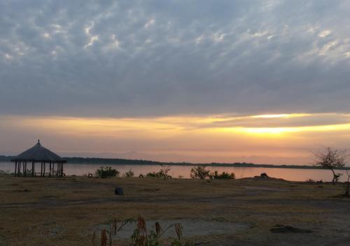 a sunset over a lake with a gazebo at Kasenyi Lake Retreat Lodges & Campsite in Kasese