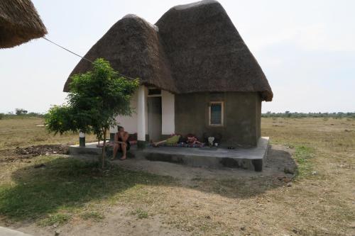 a house with a thatched roof with people sitting outside at Kasenyi Lake Retreat Lodges & Campsite in Kasese