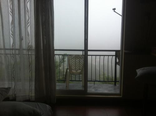a room with a window with a chair on a balcony at Witherspoon Lodge in Kandy