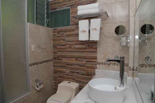 a bathroom with a sink and a toilet and towels at Sol Plaza Hotel in Puno