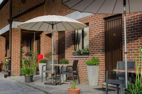 a patio with tables and chairs and an umbrella at Auberge de la Lesse in Celles