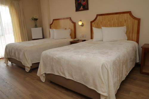 a hotel room with two beds with white sheets at Sol Plaza Hotel in Puno
