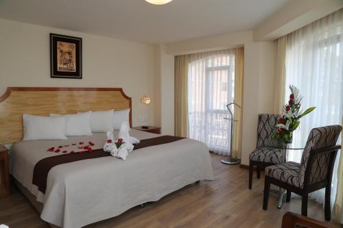 a hotel room with a large bed and two chairs at Sol Plaza Hotel in Puno