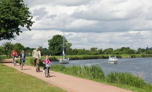 a group of people riding bikes on a path next to a river at Hotel zur Brücke in Greifswald