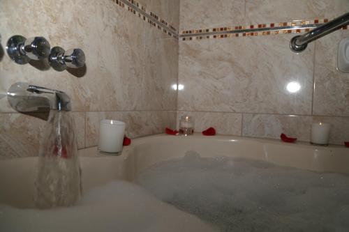 a bathroom with a bath tub with candles and a sink at Sol Plaza Hotel in Puno