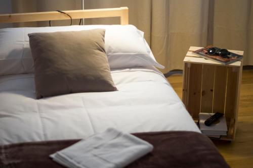 a bed with white sheets and pillows next to a table at Pension 23-Vinte e Tres in O Pedrouzo