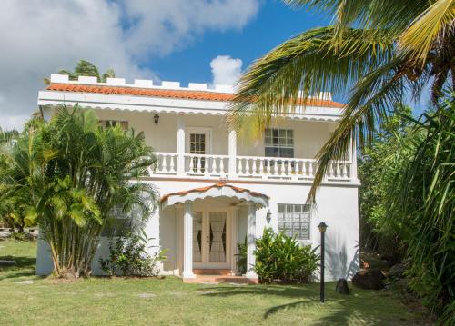 a white house with palm trees in front of it at Castles In Paradise Villa Resort in Vieux Fort