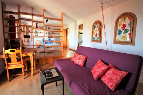 a living room with a purple couch and a bedroom at Valle y Mar, Casa de Huéspedes in La Herradura