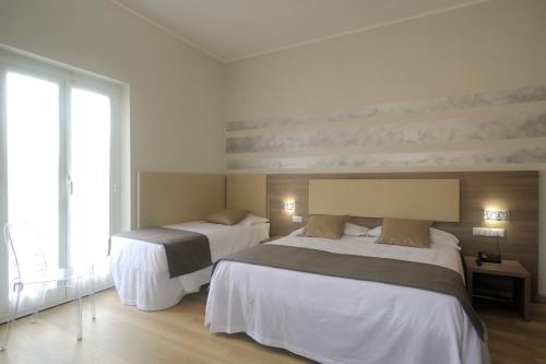 a bedroom with two beds and a large window at Albergo Anita Alassio in Alassio