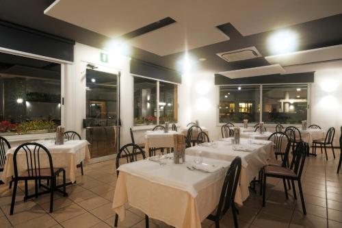 un restaurant avec des tables blanches, des chaises et des fenêtres dans l'établissement Albergo Anita Alassio, à Alassio
