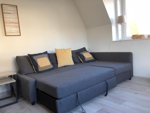 a blue couch with pillows on it in a room at De Haan in De Haan