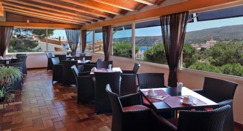 un ristorante con tavoli, sedie e ampie finestre di Hotel S´Aguarda a Cadaqués