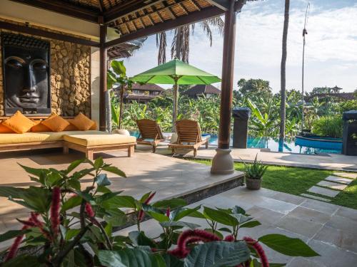 a patio with a couch and a green umbrella at Villa Nitras in Canggu