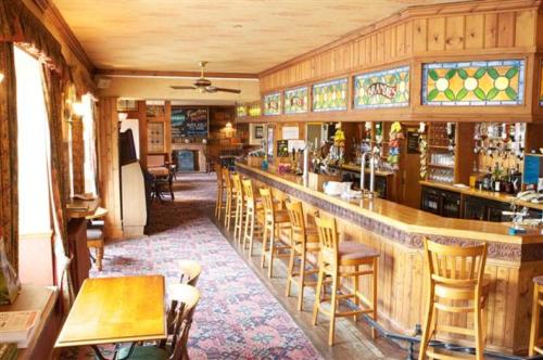 a bar in a restaurant with wooden walls and chairs at Radstock Hotel near Bath in Radstock
