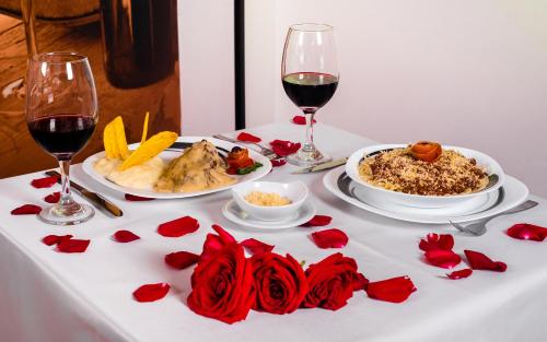 a table with two plates of food and two glasses of wine at Aw Hotel Puerta de San Antonio in Cali