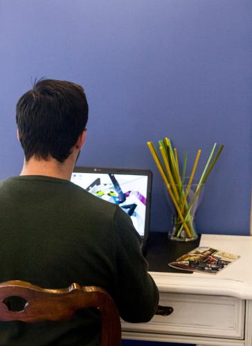 a man sitting at a desk with a laptop computer at B&B San Trifone in Adelfia