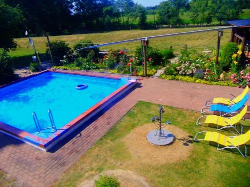 a swimming pool in a yard with two lawn chairs at Ferienwohnung JAGODA in der Lüneburger Heide in Frankenfeld