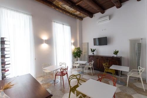 ein Wohnzimmer mit Tischen und Stühlen und einem Fernseher in der Unterkunft Savoy Riviera in Neapel