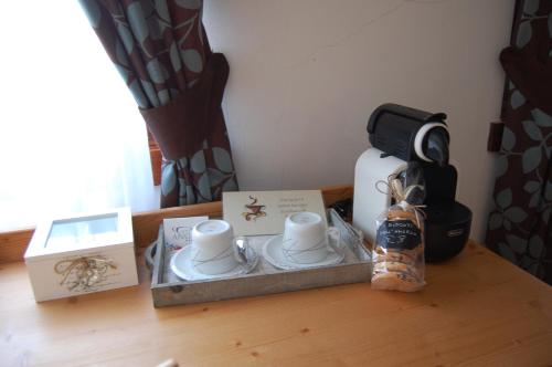 een tafel met kopjes en een koffiezetapparaat. bij Hotel Angelo in Comano Terme