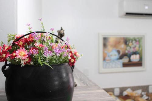 a black bucket filled with flowers on a table at Hotel Pousada Casa Tasca in Bento Gonçalves