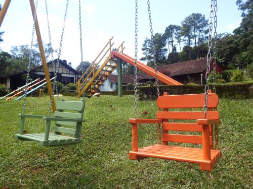 two swings in a yard with a playground at Hotel Refazenda in Visconde De Maua