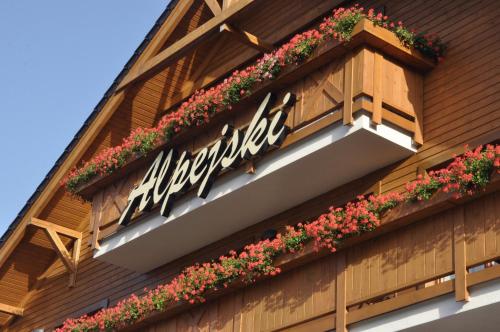 a sign on the side of a building with flowers at Hotel Alpejski in Polanica-Zdrój