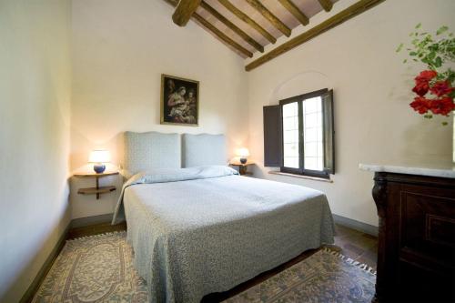 MontelopioにあるVilla Di Montelopioのベッドルーム1室(ベッド1台、ランプ2つ、窓付)