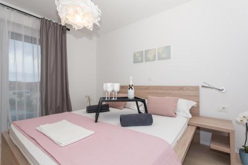 ein Schlafzimmer mit einem großen Bett mit einer rosa Decke in der Unterkunft Apartmani Pocco Locco in Biograd na Moru